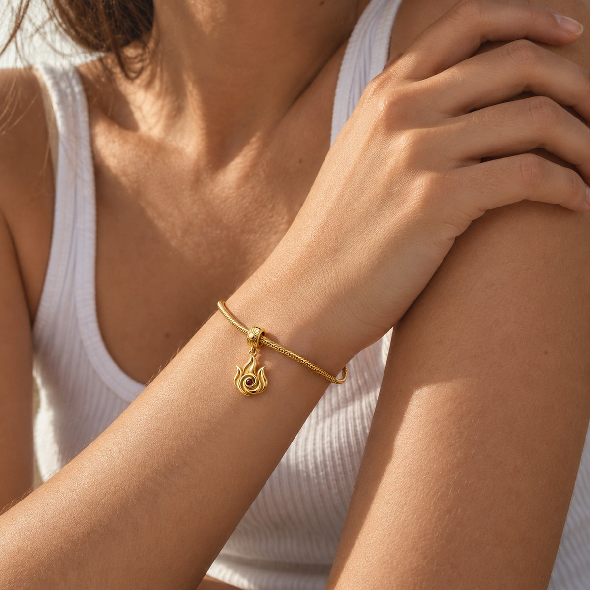 Fire Nation Flame Charm in gold, worn on a snake-chain charm bracelet
