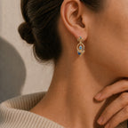 Warm close-up model photo wearing Furina-inspired gold earrings with blue gemstones