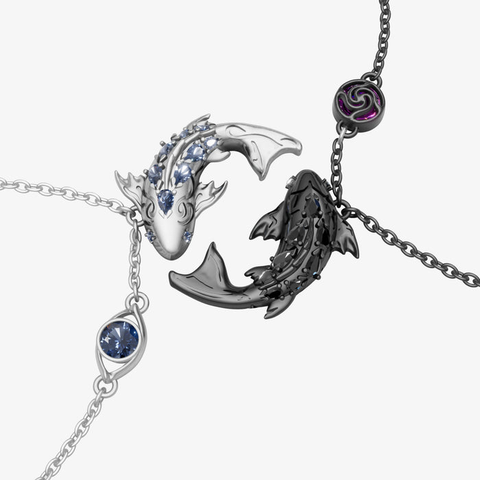 Two koi pendants on chains, one silver-tone with a blue accent and one black with a purple charm, by Kraymer Art