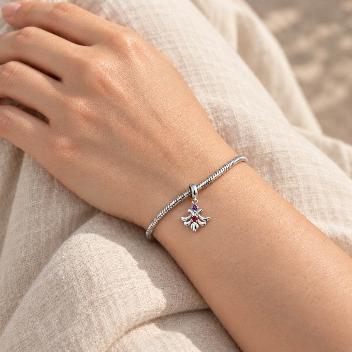 Loulan Plume Charm in silver, worn on a charm bracelet