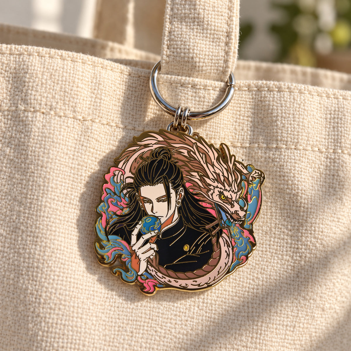 Silver pin keychain converter clipped to a canvas tote strap with an enamel pin attached