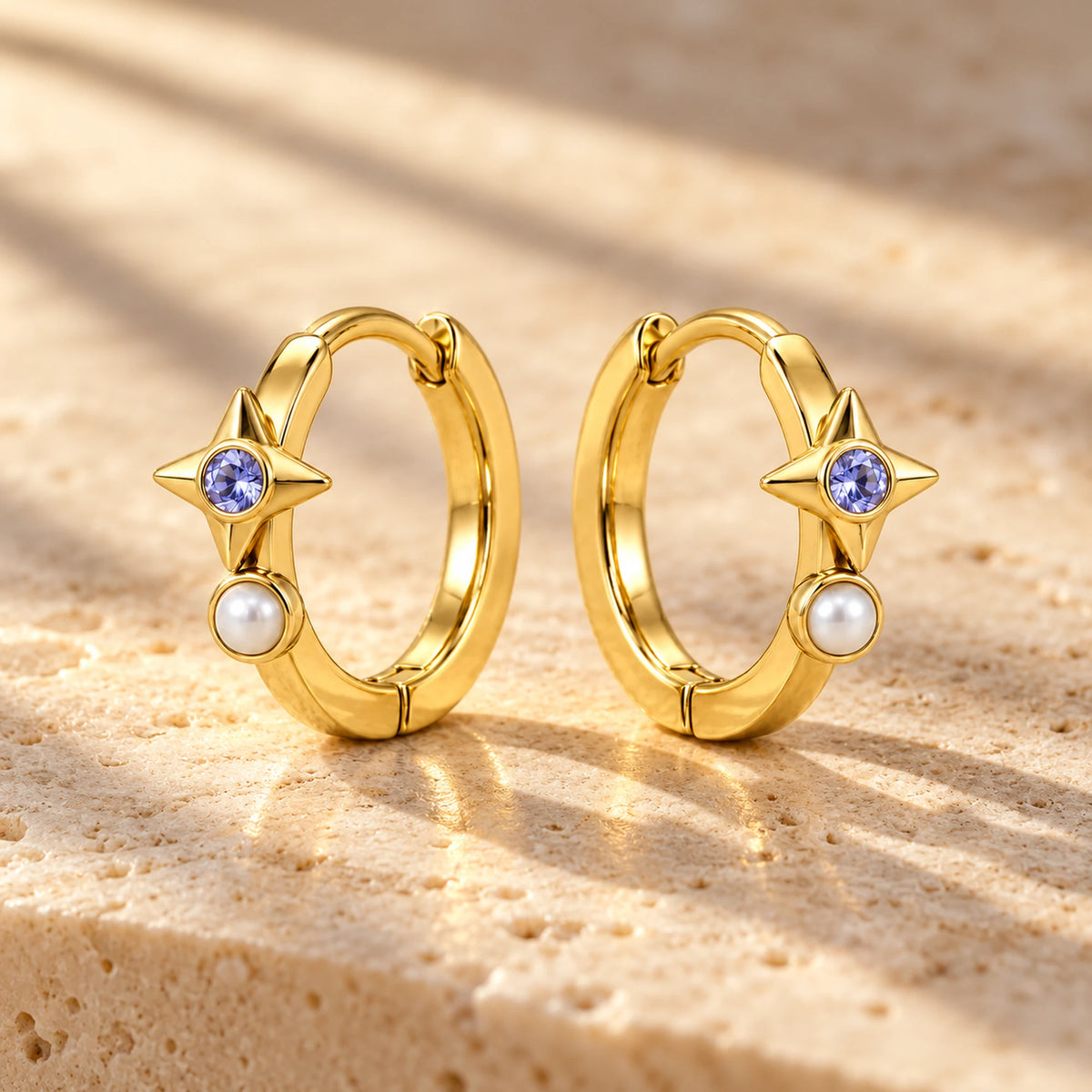 Robin Orbit Halo Huggies in gold, on warm stone in daylight